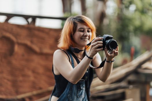 Smiling woman with dyed hair using a camera outdoors.