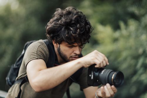 Free A focused young man with a DSLR camera photographing nature outdoors. Stock Photo