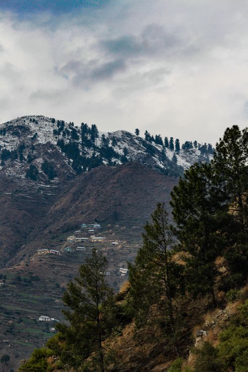 Free Scenic view of snow-capped mountains and hills with villages in Kashmir, India, under cloudy skies. Stock Photo