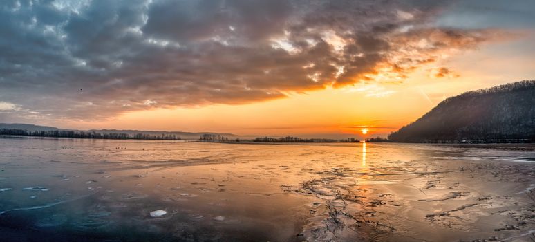 Stunning winter sunset casting warm hues over a frozen lake in Minneiska, MN