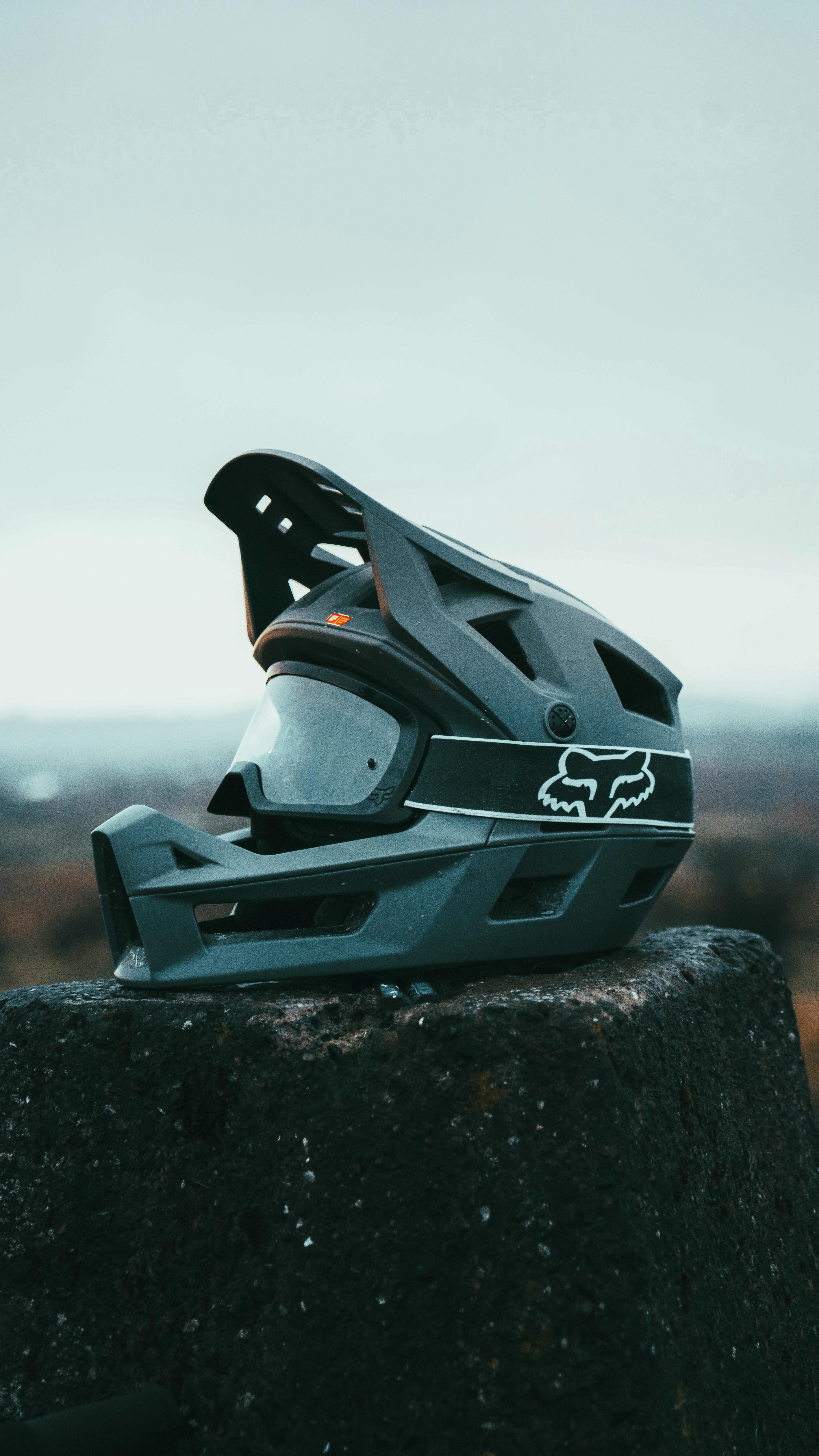 Close-up of a mountain biking helmet with goggles on a stone outdoors, showcasing protection gear.