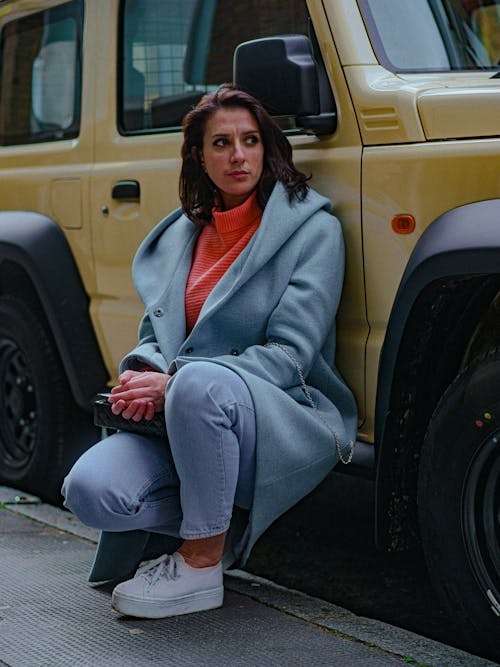 Model in a Blue Coat and a Pink Turtleneck Leaning Against a Yellow Jeep
