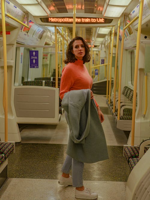 Woman in Orange Turtleneck Sweater Inside a Train 