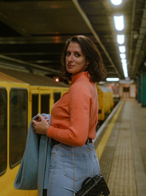 オレンジ色のセーター, きれいな女性, ジーンズの無料の写真素材