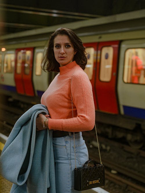 Woman in a Pink Turtleneck and Jeans on the Subway Platform