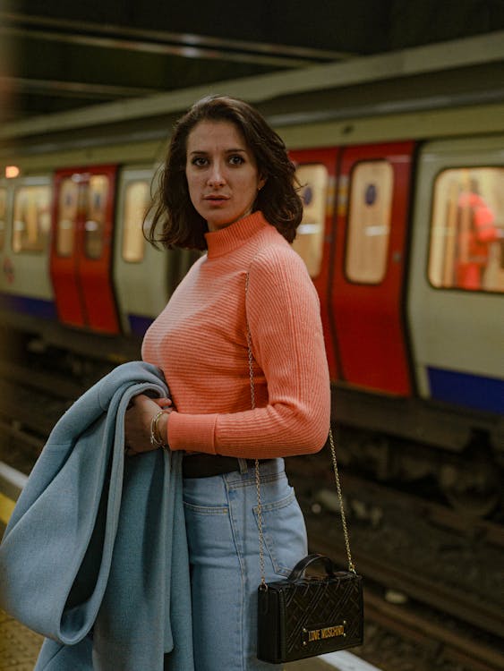 Woman in a Pink Turtleneck and Jeans on the Subway Platform