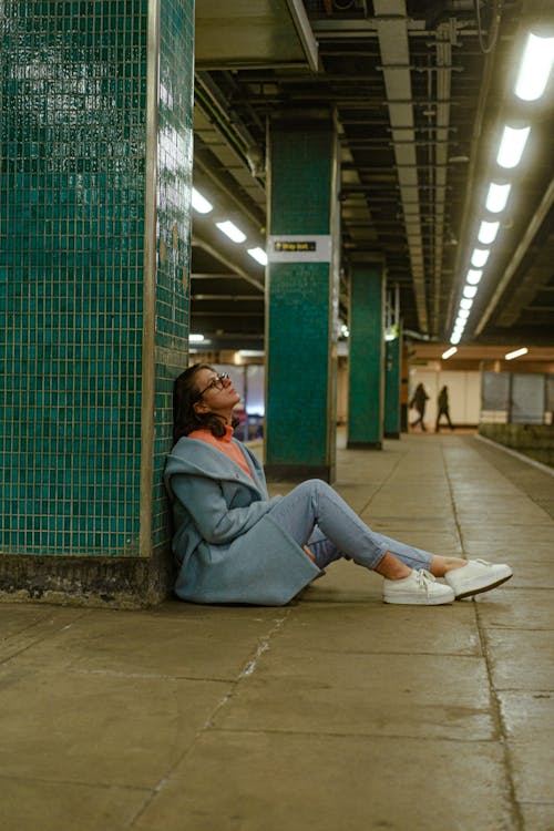Model in Blue Coat and Jeans Sitting on Subway Station Platform
