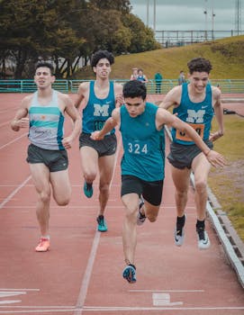 Teenage boys sprinting on an outdoor track in a competitive race setting.