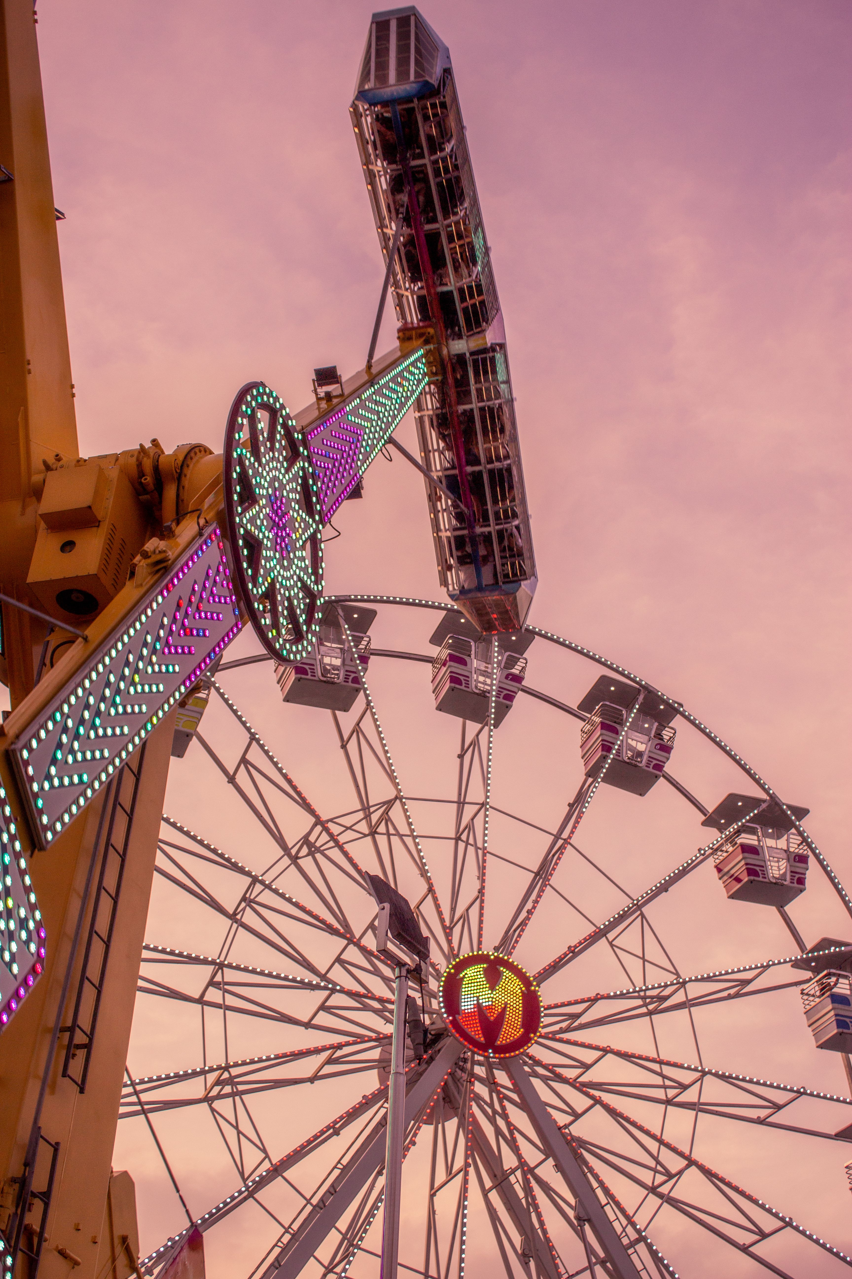 Low-angle view of a decorated Ferris wheel at sunset in a theme park.