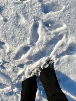Person's boots making prints in snow, captured on a sunny winter day in Saarlouis, Germany.