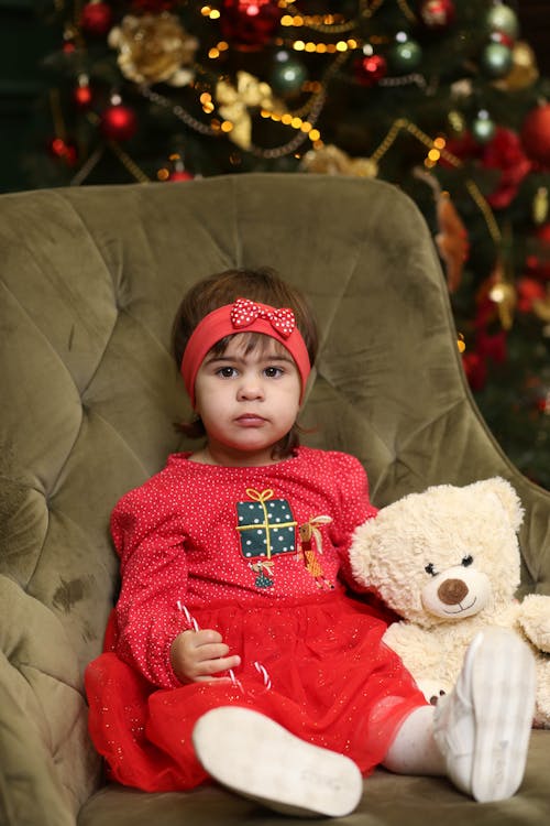 Little Girl with Teddy Bear Sitting on Armchair