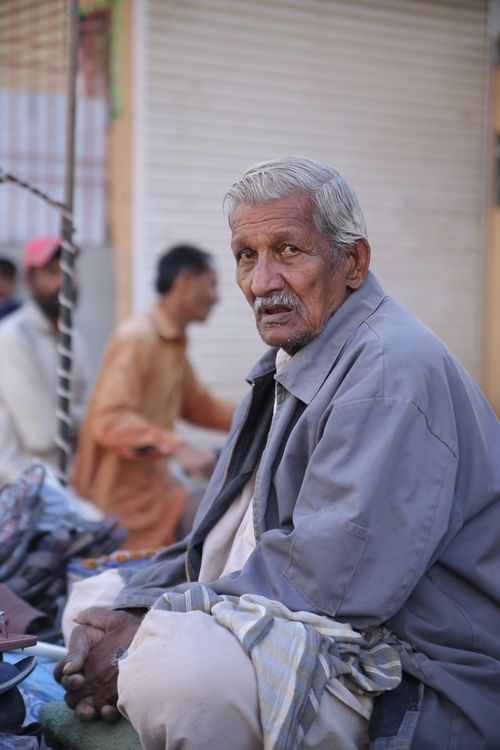 Free Senior man in blue jacket sitting at Karachi market, Pakistan. Stock Photo