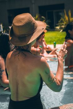 Woman in hat enjoying a drink by the pool in Tigre, Buenos Aires.