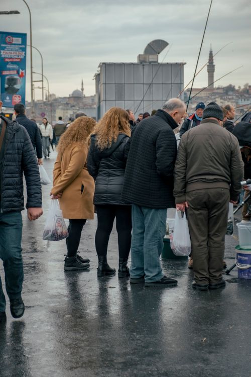 Free A group of people huddled together at an outdoor market under overcast skies, reflecting a typical urban scene. Stock Photo