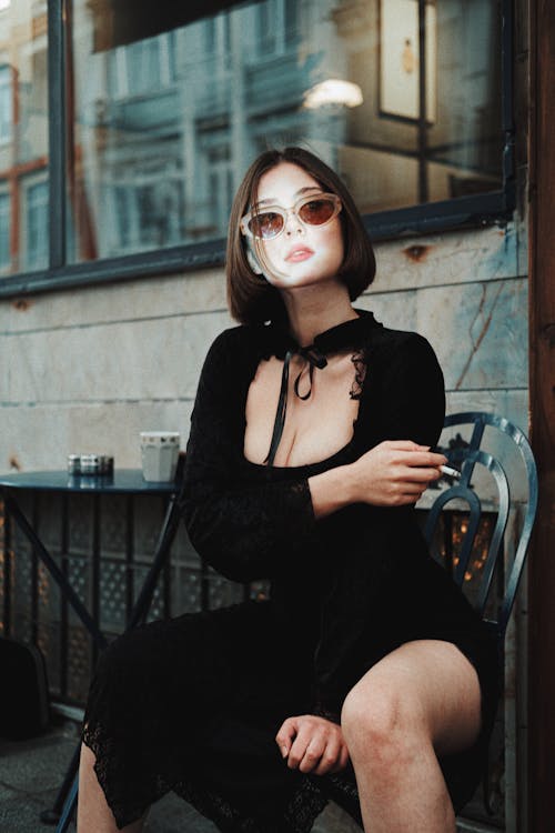 A Beautiful Woman Sitting on a Chair while Smoking Cigarette
