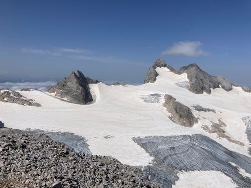 Free Breathtaking aerial shot of snow-covered mountains and glacier under clear blue skies. Stock Photo