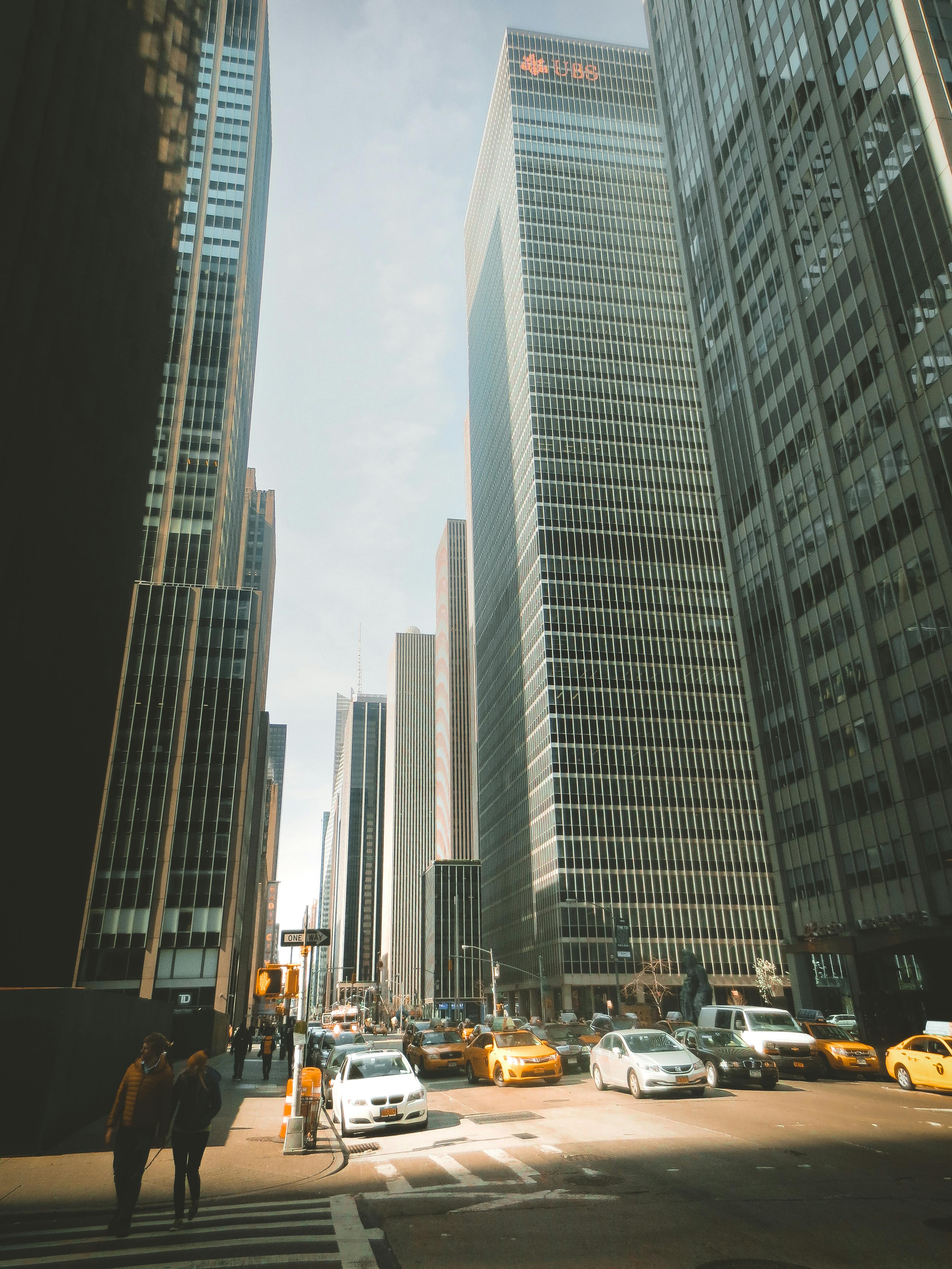 Iconic New York street scene with towering skyscrapers and busy traffic under clear skies.