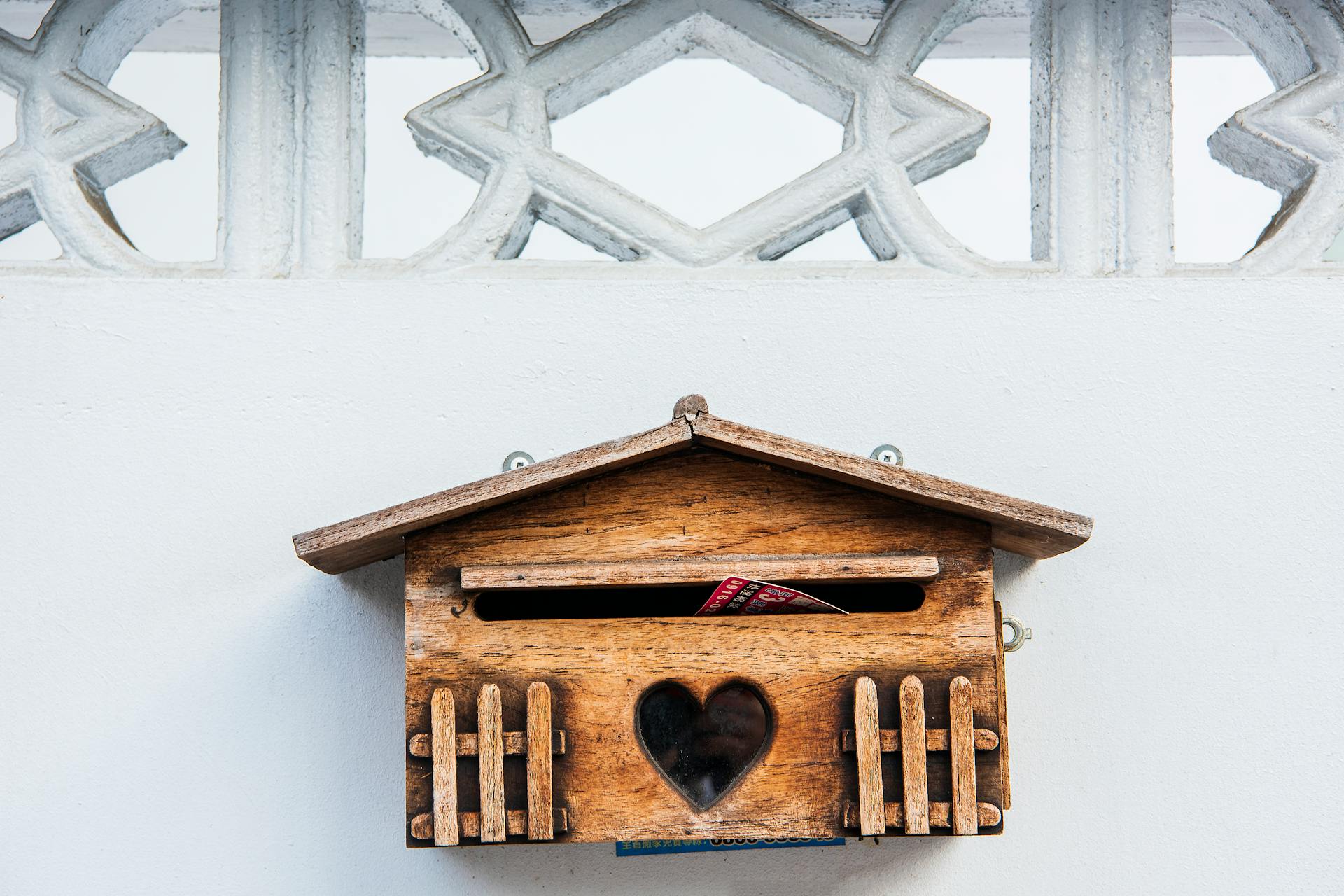 A charming wooden mailbox with heart design on a white exterior wall in Taichung, Taiwan.