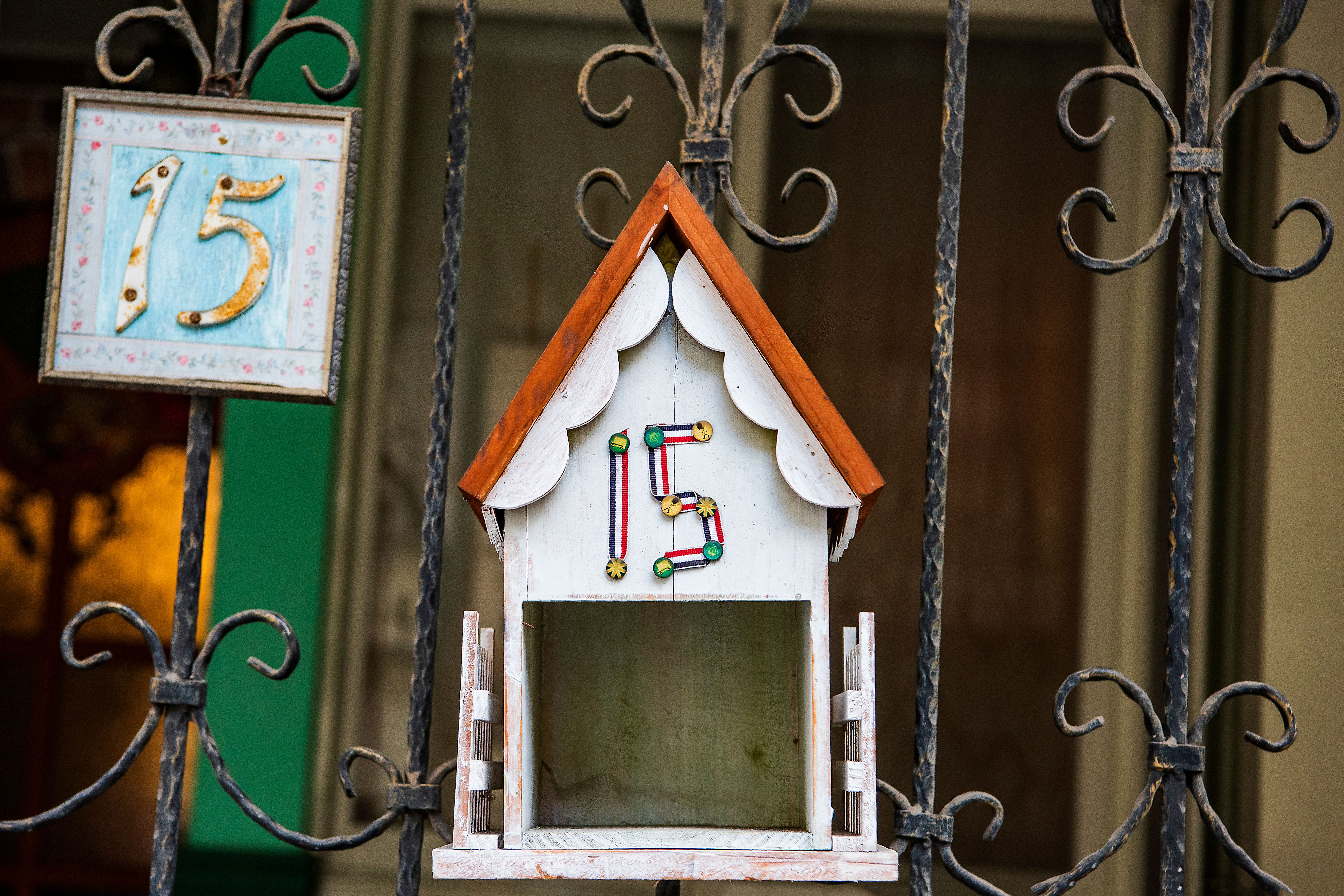 Colorful decorative letterbox attached to an ornate iron gate with house number.