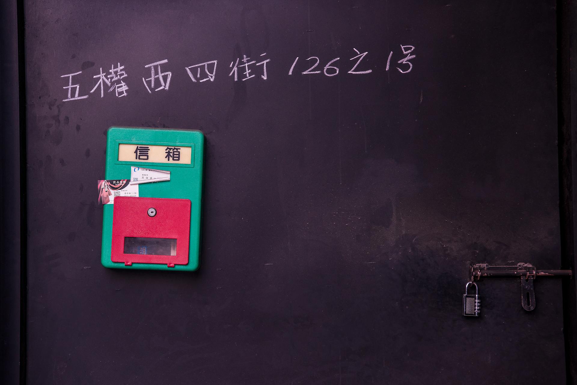 Colorful mailbox attached to a black wall, featuring a retro padlock in Taichung.