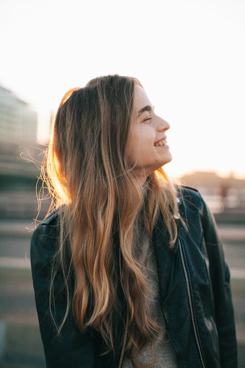 Mujer Sonriente Vistiendo Chaqueta De Cuero Negro Al Aire Libre Durante El Día