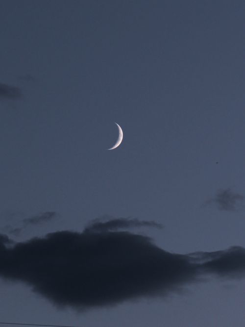 Free A peaceful crescent moon captured in the twilight sky with soft clouds creating a mystical atmosphere. Stock Photo