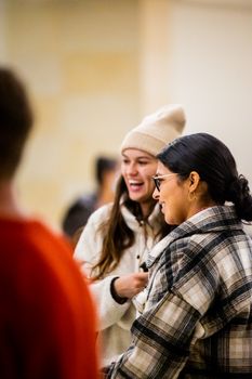Two women in a candid moment indoors, dressed warmly, sharing a laugh.