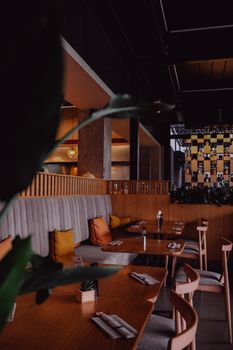 A stylish and warm restaurant interior featuring wooden tables and plush seating.