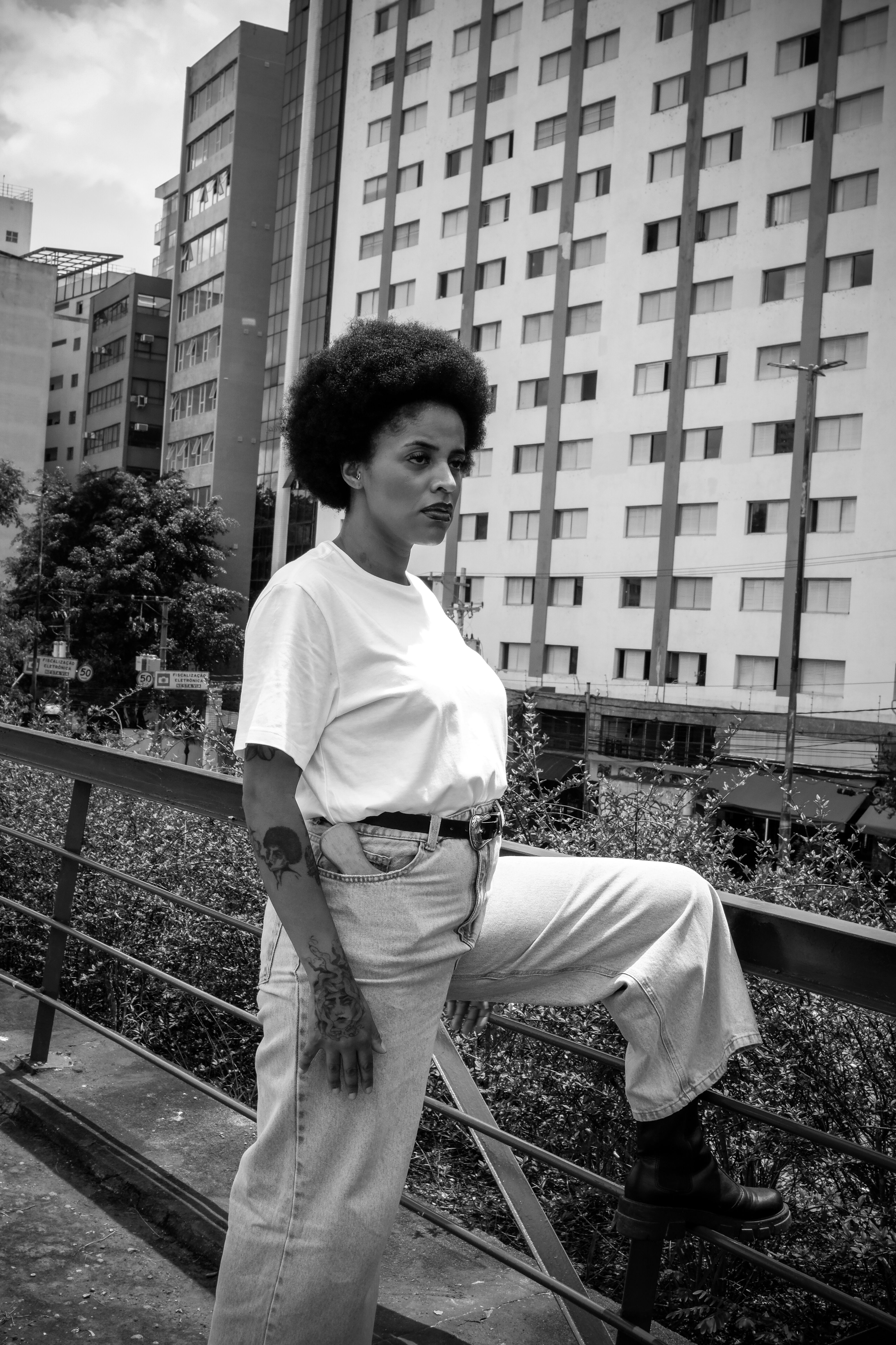 African woman posing outdoors with urban São Paulo backdrop.