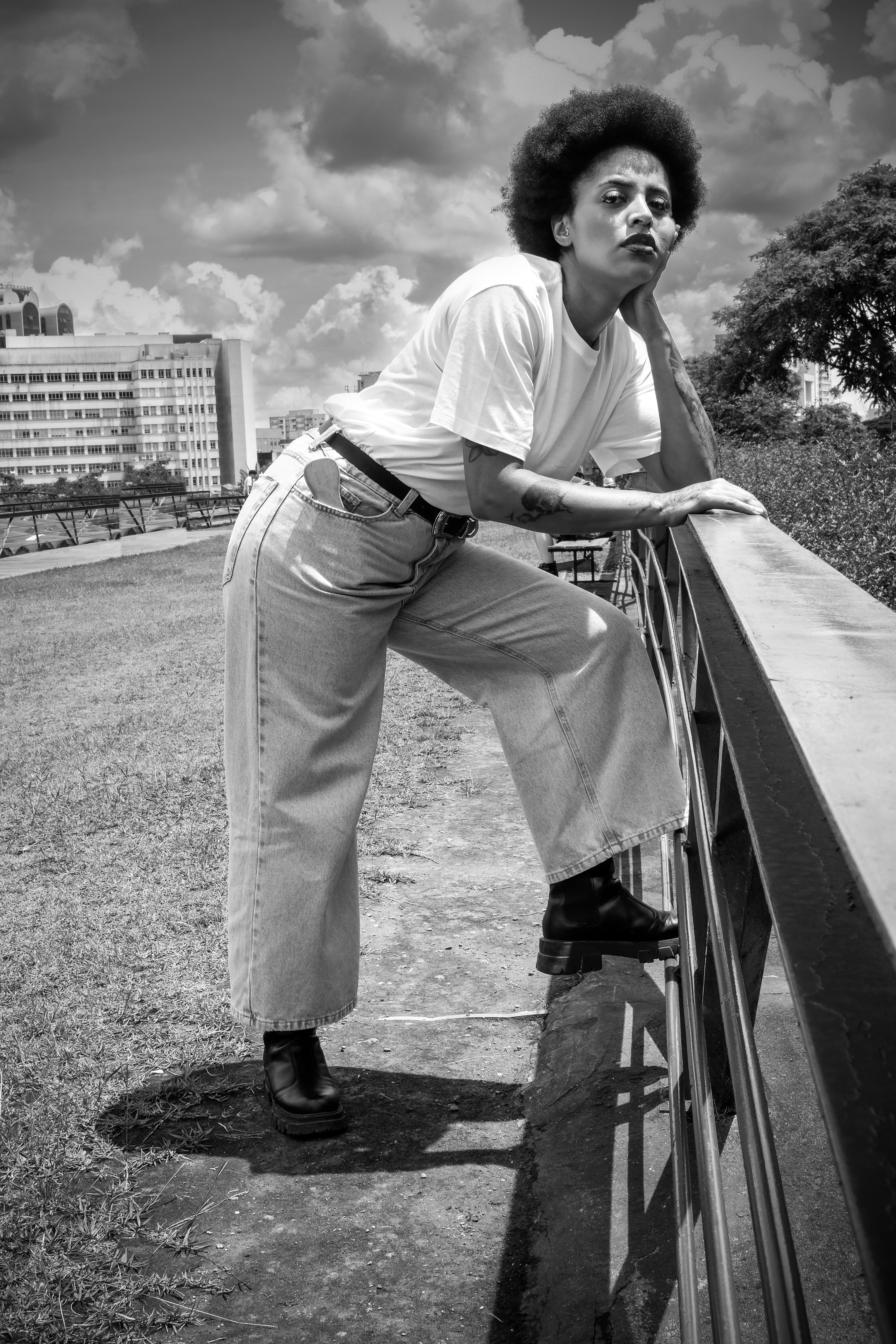Black and white photo of a woman in São Paulo, showcasing casual fashion with afro hair.