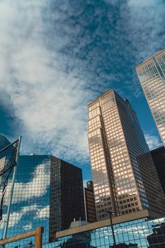 Capture of a modern city skyline with skyscrapers reflecting the cloudy sky.