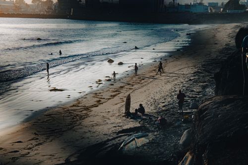 Free People enjoying a serene evening at Ensenada beach with sandy shores and gentle waves. Stock Photo