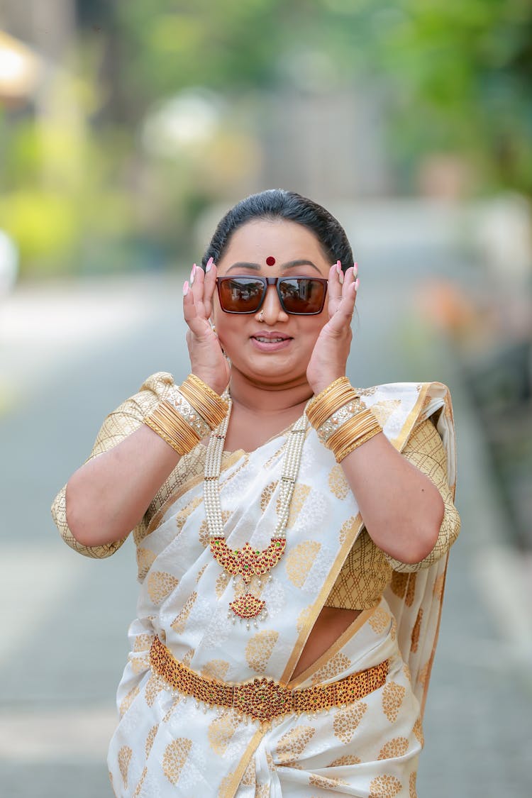 Woman In Golden Dress Trying On Sunglasses