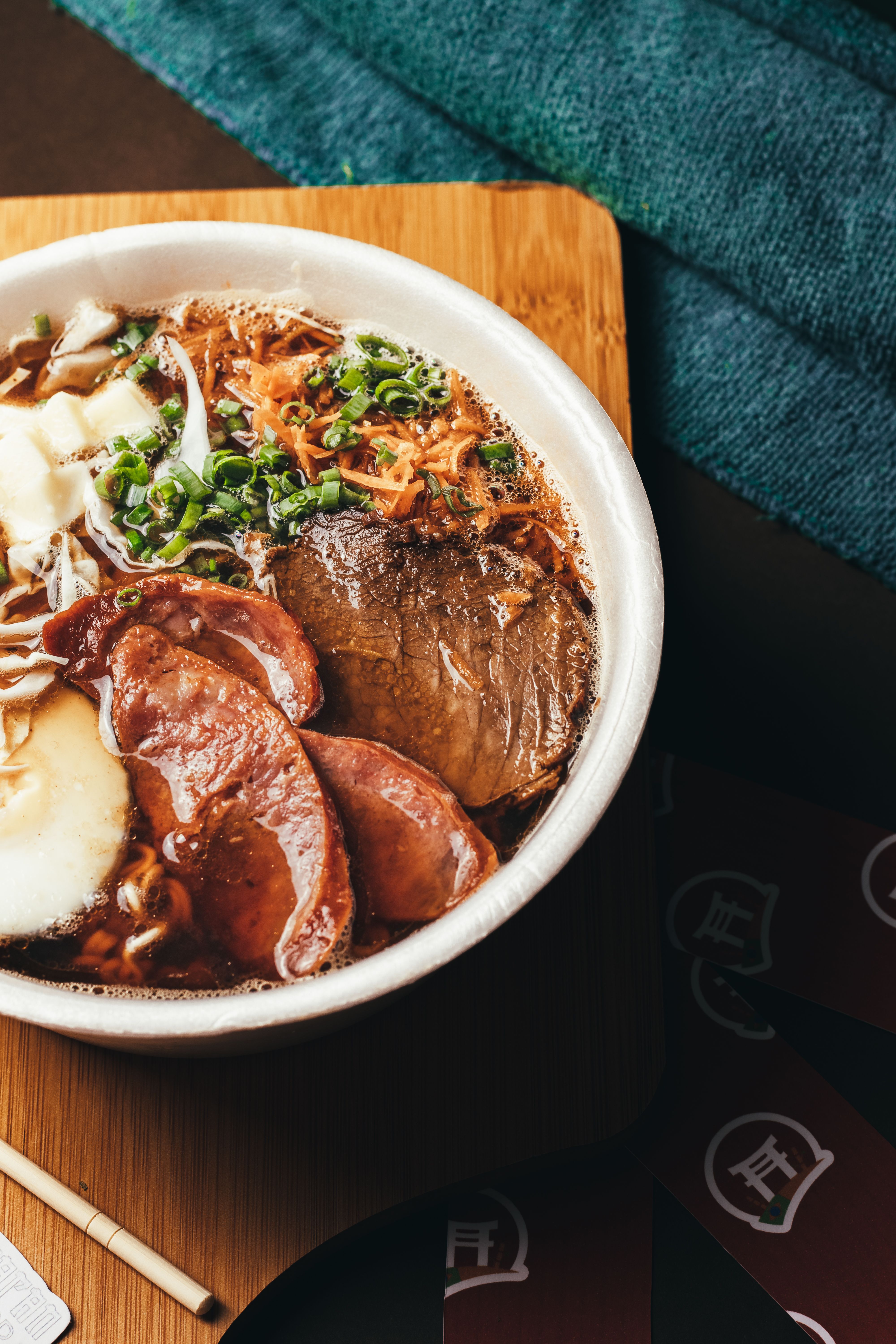 Close-up of a savory Japanese ramen bowl with meat and vegetables on a wooden table.