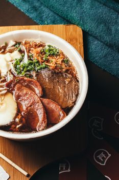 Close-up of a savory Japanese ramen bowl with meat and vegetables on a wooden table.