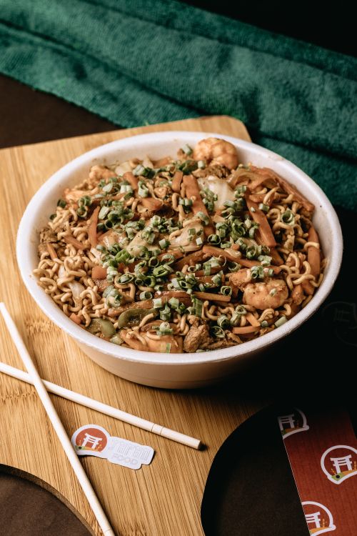 Free Close-up of a bowl of Asian style instant noodles with vegetables and shrimp, using chopsticks. Stock Photo