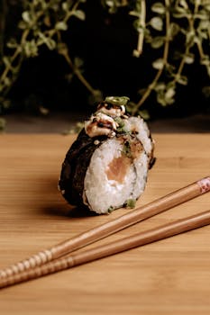 Mouth-watering salmon sushi roll with chopsticks on bamboo mat, perfect for food photography.