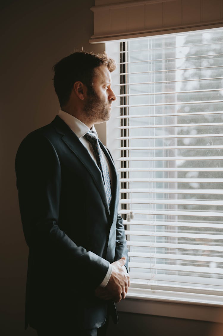 Man In A Suit Standing And Looking Through The Window 