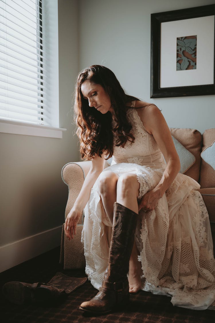 Woman In A Wedding Dress Putting On Boots 