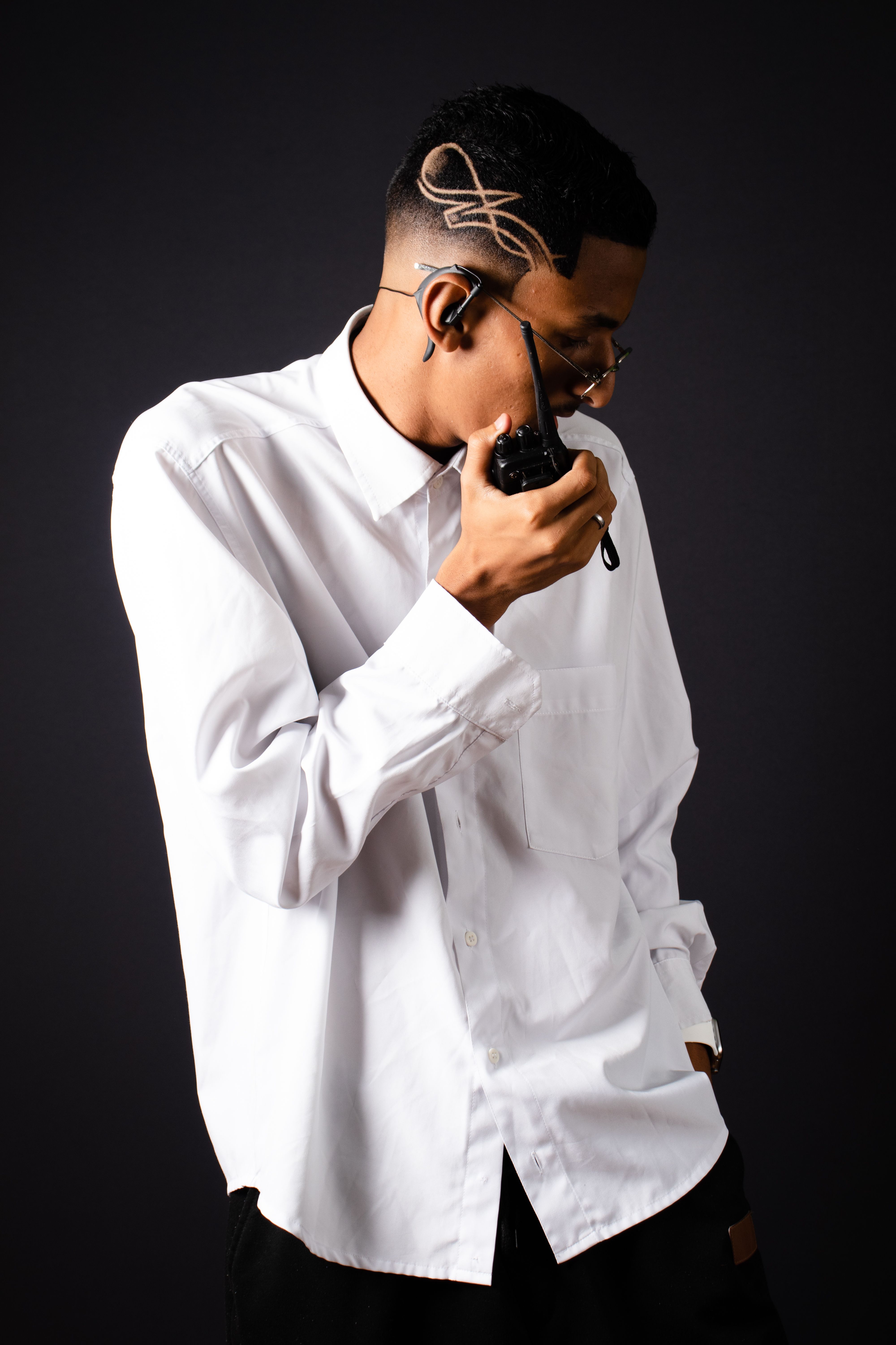Stylish young man in a white shirt using a walkie talkie, showcasing modern communication tech.