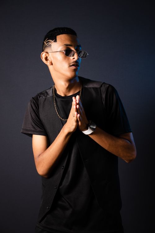 Free Fashionable young man posing confidently in sunglasses and black attire against a dark background. Stock Photo