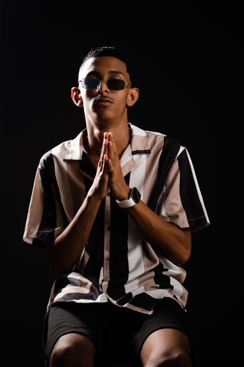 Free Portrait of a man in sunglasses and striped shirt on black background, stylish pose. Stock Photo