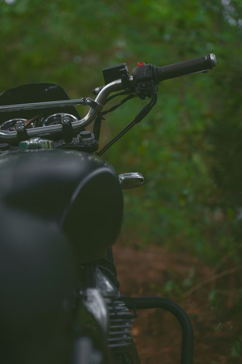 Free Focused view of a classic motorcycle handlebar surrounded by greenery. Stock Photo