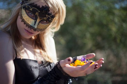 Woman in Costume Mask Holding Petals in Hands