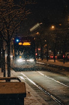 A tram navigates a snow-covered street in Toronto during a winter night, capturing the essence of urban winter travel.