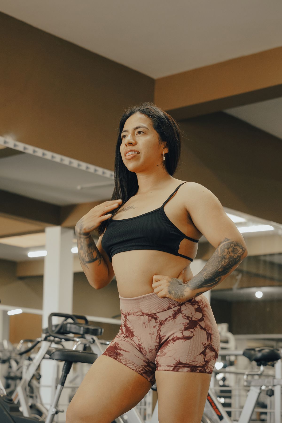 Woman wearing a black top and cycling shorts in a gym