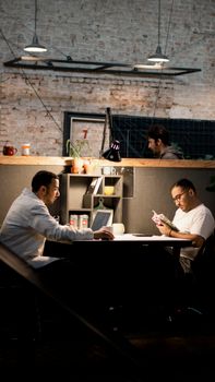 Two men relaxing and reading in a modern Tehran café. Cozy indoor ambiance.