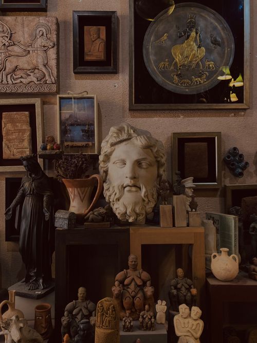 Free A captivating arrangement of ancient sculptures and framed wall art in a museum exhibit. Stock Photo