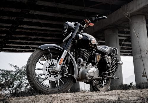 Free Low angle shot of a Royal Enfield motorcycle parked under a bridge in Noida, India. Stock Photo