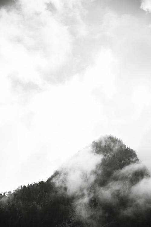 Grayscale Photo of Mountain Peak and Clouds